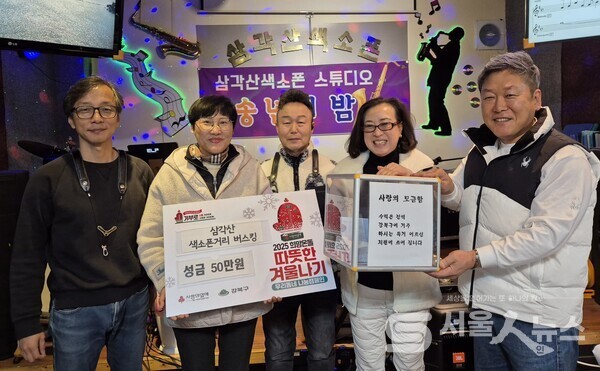 ▲성도연 회장(우 2)과 김진미 우이동 동장(좌 2)이 최봉식 단장(우측 1)과 삼각산 색소폰 스튜디오에서 불우이웃 돕기 성금 전달식에 참석해 기념사진을 촬영하고 있다.