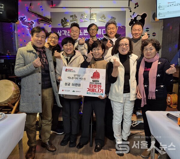 ▲성도연 회장(앞줄 우 2)과 김진미 우이동 동장(앞줄 좌 2)이 삼각산 색소폰 스튜디오에서 불우이웃 돕기 성금 전달식의 참석한 동호회 임원들과 기념사진을 촬영하고 있다.