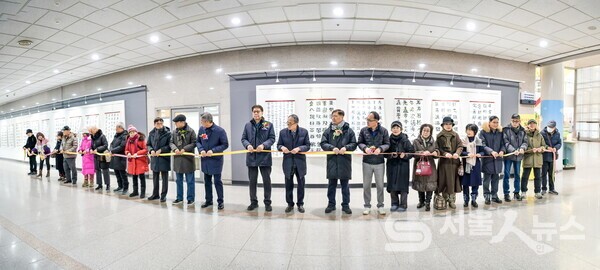 ▴이정호 작가(우 11)와 내⋅외빈, 도봉1동 서예반 수강생들이 함께 전시회 개막에서 테이프커팅식을 진행하고 있는 모습.(사진제공=정나연 사진작가)