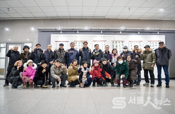 ▴이정호 작가(뒷줄 좌 4)와 내⋅외빈, 도봉1동 서예반 수강생들이 파이팅을 외치며 단체사진을 찍고 있다.(사진제공=정나연 사진작가)