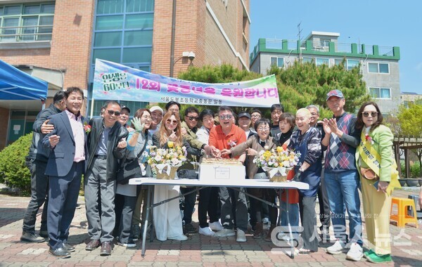 ▲김명곤 총동문회장(좌 1)이 바자회 행사에서 환갑을 맞이한 동문들을 위해 떡 케이크로 이벤트를 진행하며 기념사진을 찍고 있다.