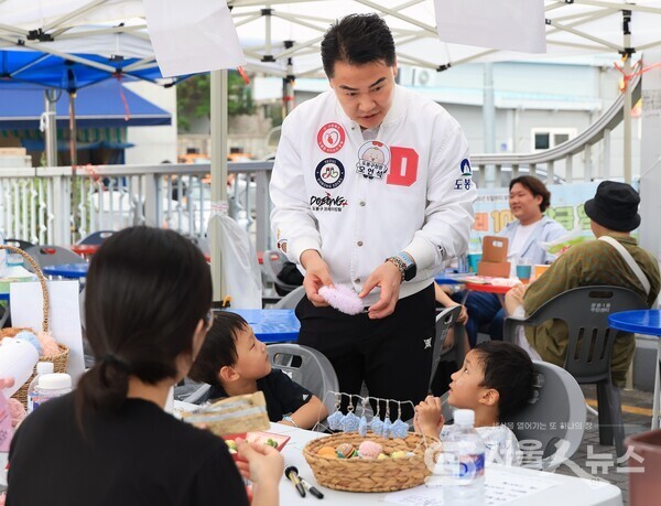 ▲오언석 도봉구청장(가운데)이 지난 8월 31일 열린 백운시장 벼룩시장 행사에서 체험 프로그램에 참여 중인 아이와 대화를 나누고 있다(2025. 8. 31. 백운시장)